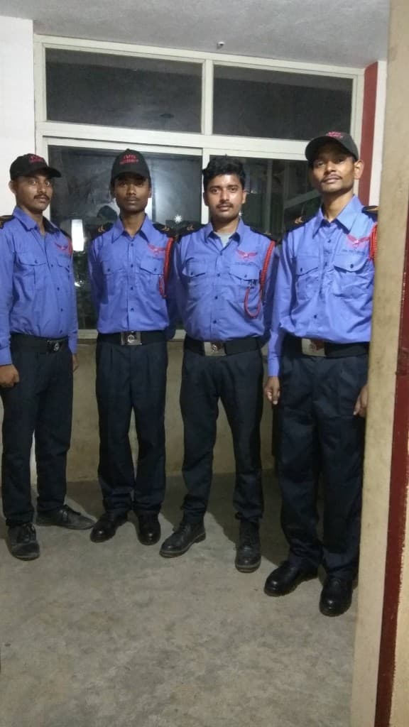 Four IVS Security guards in matching uniforms standing indoors